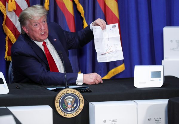 President Donald Trump holds up a chart on global coronavirus disease (COVID-19) testing as he sits in front of coronavirus testing machines in Phoenix, Arizona, United States, 5 May 2020 (Photo: Reuters/Tom Brenner).
