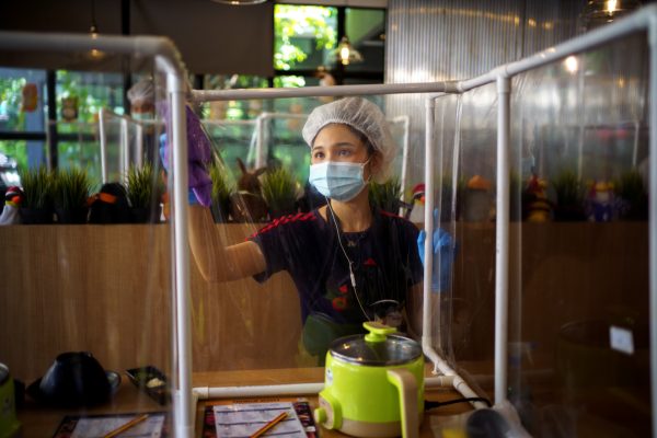 A worker cleans a plastic barrier after customers had lunch at the Penguin Eat Shabu hotpot restaurant that reopened after the easing of restrictions with the implementation of a plastic barrier and social distancing measures to prevent the spread of the coronavirus disease (COVID-19) in Bangkok, Thailand, 8 May, 2020 (Photo:Reuters/Athit Perawongmetha).