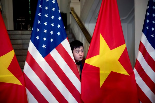 A worker helps arrange US and Vietnamese flags before US Secretary of State Mike Pompeo and Vietnamese Foreign Minister Pham Binh Minh arrive for a meeting at the Ministry of Foreign Affairs in Hanoi, Vietnam, 26 February 2019 (Photo: Reuters/Andrew Harnik).