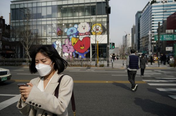 A woman wearing a mask to prevent the coronavirus uses her mobile phone at a shopping district in Seoul, South Korea, 24 February, 2020 (Photo: Reuters/Kim).