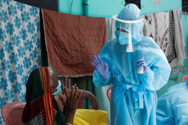 A healthcare worker wearing personal protective equipment (PPE) speaks to a resident about the coronavirus disease (COVID-19) at a check up camp in Dharavi, one of Asia's largest slums, Mumbai, India, 7 June 2020 (Reuters/Francis Mascarenhas).