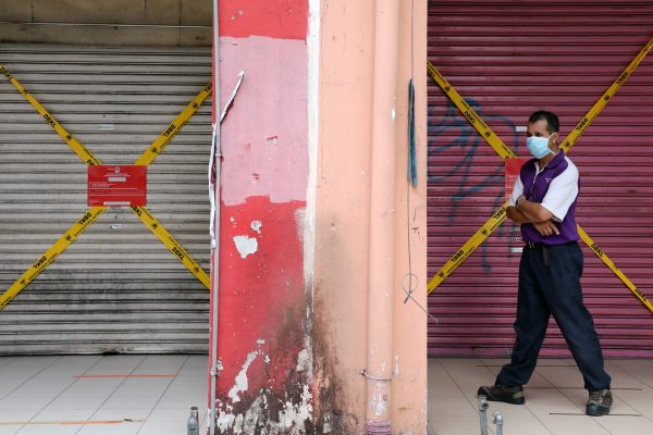 A man wearing a protective mask walks past closed shops amid the COVID-19 outbreak in Kuala Lumpur, Malaysia, 28 May 2020 (Photo: Reuters/Lim Huey Teng).