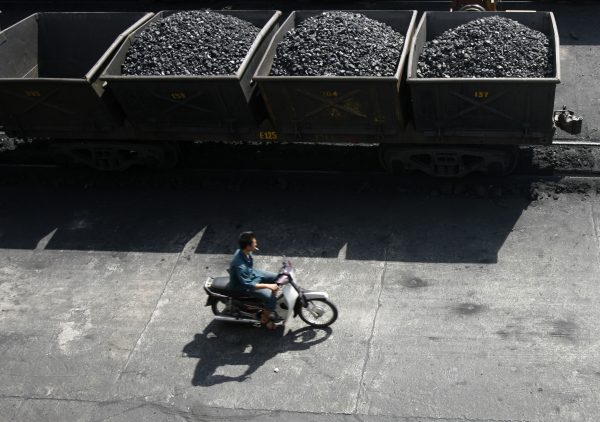 A worker rides his motorcycle near lorries transporting coal at a port of the Cua Ong Coal Preparation Company in Cam Pha town, Quang Ninh, Vietnam (Photo: Reuters/Kham).