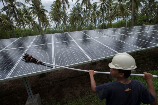 An employee of PT Perusahaan Listrik Negara (PLN) cleans the surface of solar panels at a solar power generation plant in Gili Meno island, in this 9 December 2014 photo taken by Antara Foto (Reuters/Antara Foto/Widodo S. Jusuf.).