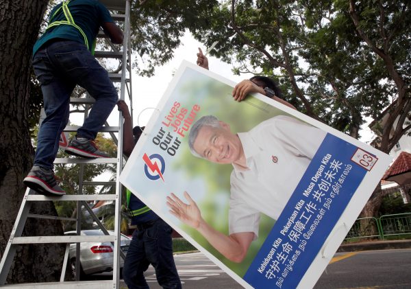 Workers hang up electoral poster for ruling People's Action Party ahead of the general election in Singapore, 30 June 2020 (Photo: Reuters/Edgar Su).