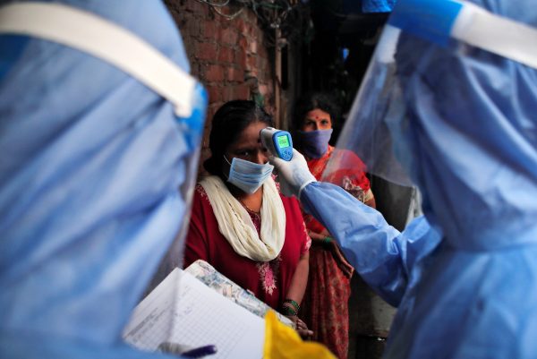 A healthcare worker checks the temperature of a woman using an electronic thermometer during a check up campaign for the coronavirus disease (COVID-19) at a slum area in Mumbai, India 8 July, 2020 (Photo:Reuters/Francis Mascarenhas).