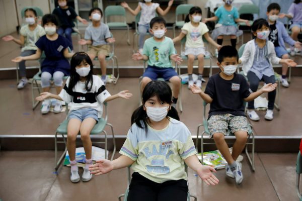 Students wearing protective face masks amid the coronavirus disease (COVID-19) outbreak, clap along instead of singing a song during a music class at Takanedai Daisan elementary school, which practices various methods of social distancing in order to prevent the infection, in Funabashi, east of Tokyo, Japan 16 July, 2020 (Photo: Reuters/Kim).