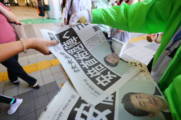 People receive an extra edition of newspaper reporting Japanese Prime Minister Shinzo Abe to resign his post due to his health concerns in Tokyo, Japan, 28 August 2020 (Photo: Naoki Nishimura/AFLO via Reuters).