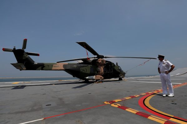 An Australian Navy officer from Australian Landing Helicopter Dock (LHD) ship, HMAS Canberra stands next to a helicopter after arriving at the main harbour in Colombo, Sri Lanka 23 March, 2019. (Photo: Reuters/Dinuka Liyanawatte).