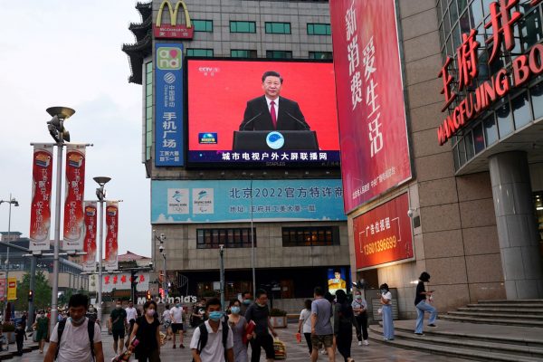 People wearing face masks following the coronavirus disease (COVID-19) outbreak, walk past a giant screen broadcasting a news footage of Chinese President Xi Jinping at a shopping area in Beijing, China, 31 July 2020 (Photo: Reuters/Tingshu Wang).