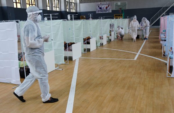 Medical specialists wearing personal protective equipment (PPE) treat patients at a day hospital, located in a school gym and provides services free of charge, in Bishkek, Kyrgyzstan, 16 July 2020 (Author: Reuters/Vladimir Pirogov).
