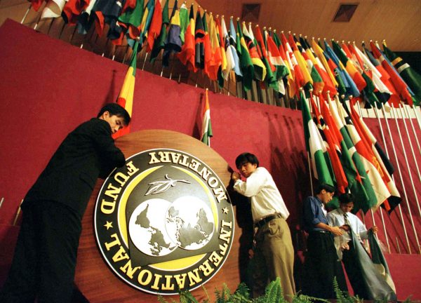 Workers remove the International Monetary Fund (IMF) emblem and nation flags from the podium after a World Bank/IMF ceremony in Hong Kong (Photo: Reuters).