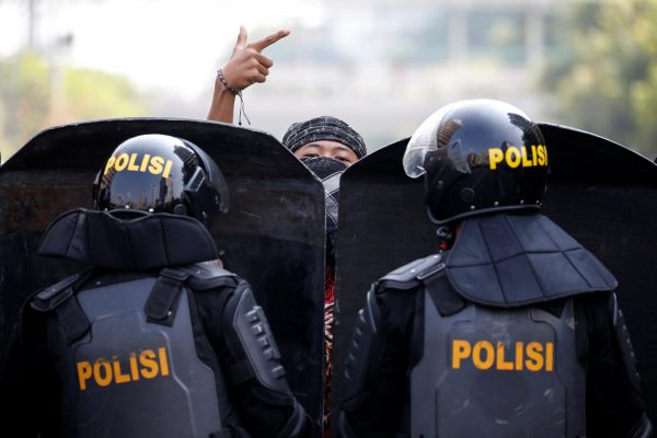 A protester gestures as mobile brigade (Brimob) police officers stand guard at a barricade during a protest in Jakarta, Indonesia, 22 May 2019 (Photo: Reuters/Willy Kurniawan).