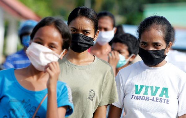 Women wearing protective masks look on as they walk on a street after the government announced new cases of coronavirus disease (COVID-19), in Dili, East Timor, 16 April, 2020. (Reuters/Lirio da Fonseca).