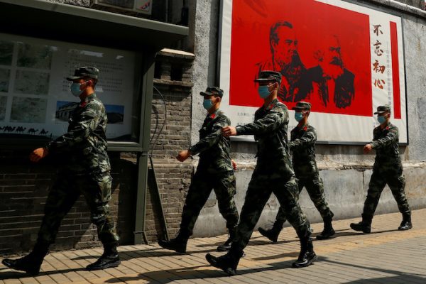 Chinese servicemen walk past portraits of German philosophers Karl Marx and Friedrich Engels and patrol a street near the Great Hall of the People on the opening day of the National People's Congress (NPC) following the outbreak of the coronavirus disease (COVID-19), in Beijing, China 22 May, 2020 (Photo:Reuters/Thomas Peter).