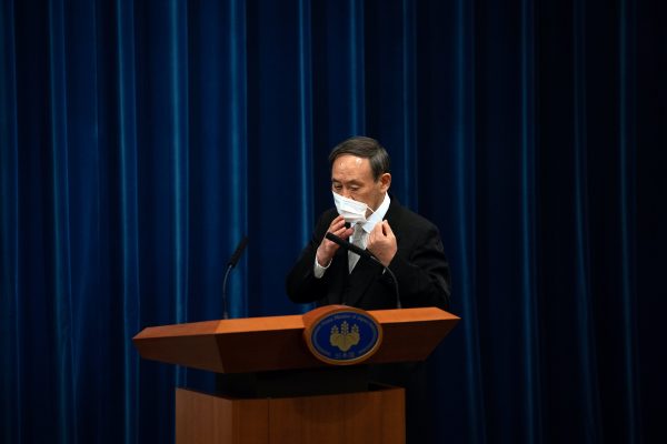 Yoshihide Suga removes his face mask as he arrives to attend a press conference following his confirmation as Prime Minister of Japan, in Tokyo, Japan, 16 September, 2020 (Carl Court/Pool via Reuters).