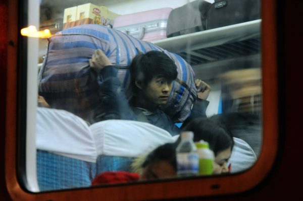 A Chinese migrant worker carries his luggage in a train as he heads back home for the Chinese Lunar New Year or Spring Festival at the Qingdao Railway Station in Qingdao City, east China's Shandong province, 13 February, 2015 (Reuters).