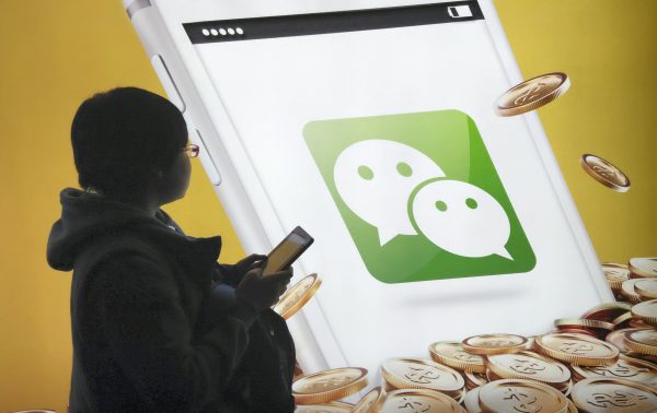 A pedestrian looks at an advertisement for the mobile messaging app Weixin, or WeChat, of Tencent in Beijing, China, 16 February 2015 (Photo: Reuters/Wu Changqing).