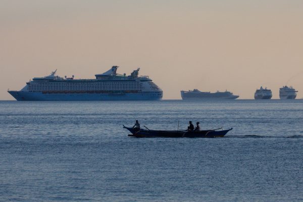 Fishermen sail past a group of cruise ships anchored in Manila Bay as its crew members undergo quarantine amid the coronavirus disease (COVID-19) outbreak, in Manila, Philippines, 8 May 2020 (Photo: Reuters/Eloisa Lopez).