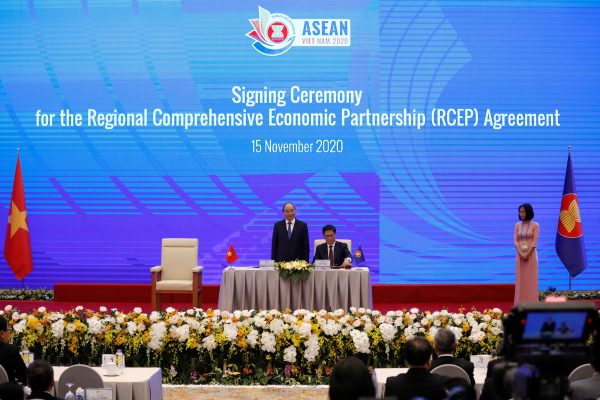 Vietnam's Industry and Trade Minister Tran Tuan Anh (C) signs as Vietnam's Prime Minister Nguyen Xuan Phuc (L) witnesses during the signing ceremony of the Regional Comprehensive Economic Partnership (RCEP) Agreement during the 37th ASEAN Summit in Hanoi, Vietnam 15 November 2020. (Photo: Reuters/Kham).