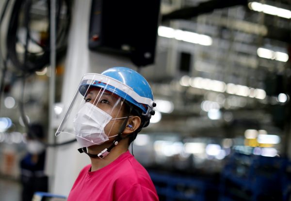 An employee wearing a protective face mask and face guard works on the automobile assembly line as the maker ramps up car production with new security and health measures as a step to resume full operations, during the outbreak of the coronavirus disease (COVID-19), at Kawasaki factory of Mitsubishi Fuso Truck and Bus Corp., owned by Germany-based Daimler AG, in Kawasaki, south of Tokyo, Japan, 18 May, 2020 (Photo: Reuters/Issei Kato/File Photo).