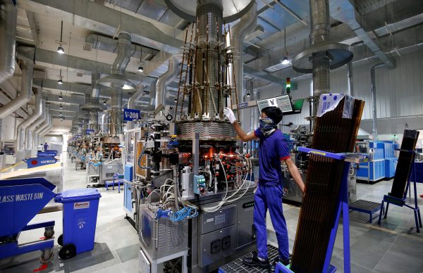 An employee fills glass tubes in a vial making machine inside a manufacturing unit of Schott Kaisha, India's largest vial manufacturer, in Jambusar in the western state of Gujarat, India, 1 December 2020. (Photo: Reuters/Amit Dave).