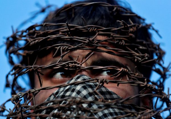 A masked Kashmiri man with his head covered with barbed wire attends a protest after Friday prayers during restrictions following the scrapping of the special constitutional status for Kashmir by the Indian government, in Srinagar, 11 October 2019 (Photo: Reuters/Danish Ismail).