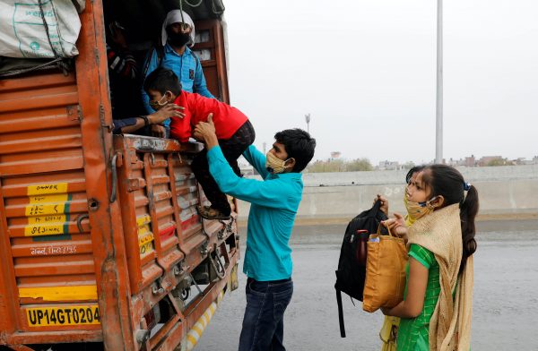 Sushil Kumar, a migrant worker, helps his son get inside a truck as he returns to his village wit his family, during a 21-day nationwide lockdown to limit the spreading of coronavirus disease (COVID-19), in Ghaziabad, on the outskirts of New Delhi, 27 March, 2020 (Photo: Reuters/Adnan Abidi).