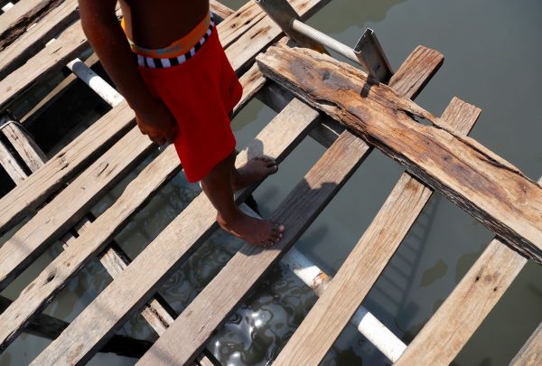A boy stands on a wooden path between stilt houses at Hanuabada Village, Papua New Guinea (Photo: Reuters/David Gray).