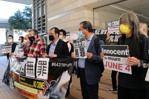Pro-democracy activists Lee Cheuk-yan and Leung Kwok-hung, also known as 'Long Hair', hold placards outside West Kowloon Magistrates' Courts before facing charges related to an illegal vigil assembly commemorating the 1989 Tiananmen Square crackdown, in Hong Kong, 5 February 2021 (Photo: Reuters/Tyrone Siu).