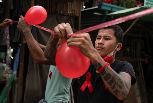 People wearing red ribbons attach balloons during a protest against the military coup in Yangon, Myanmar, 5 February 2021 (Photo: Reuters/Stringer).