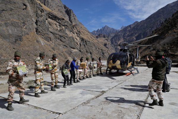 Members of Indo-Tibetan Border Police (ITBP) unload relief goods at a temporary base camp set up by ITBP for distribution of relief material in the affected areas, after a flash flood swept a mountain valley destroying dams and bridges, at Lata village in Chamoli district, northern state of Uttarakhand, India, 12 February 2021 (Photo: Reuters/Anushree Fadnavis).