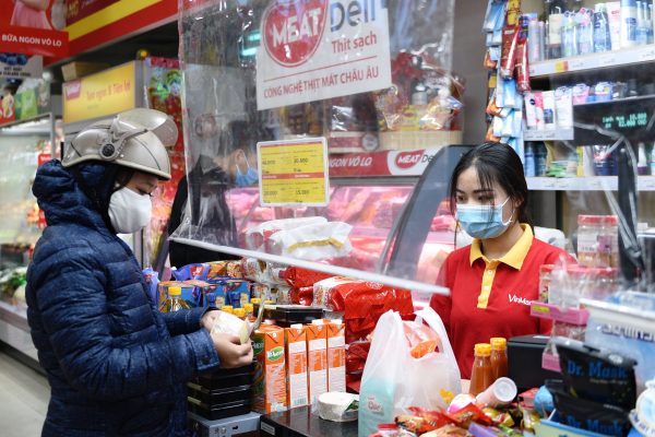 A customer pays in a corner shop where a plastic divider is installed as a measure against the spread of the coronavirus disease (COVID-19) at a shop in Hanoi, Vietnam, 18 February, 2021 (Photo: Reuters/Thanh Hue).