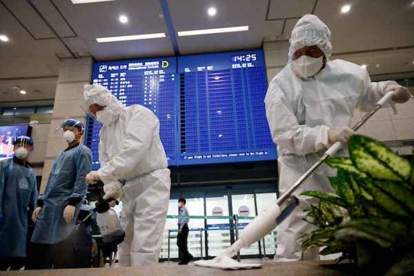 Workers wearing protective gear disinfect an arrival gate as an electronic board shows arrivals' information amid the coronavirus disease (COVID-19) pandemic at the Incheon International Airport in Incheon, South Korea, 28 December, 2020 (Photo: Reuters/Kim Hong-Ji).