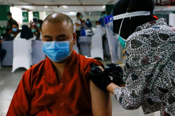 A monk reacts while receiving China's Sinovac Biotech vaccine for COVID-19 at the parking lot of Grand Istiqlal Mosque in Jakarta, Indonesia, 25 February 2021 (Reuters/Ajeng Dinar Ulfiana).