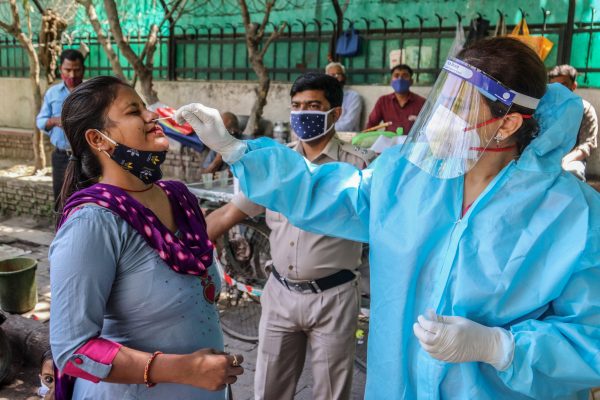 A health worker collects swab samples from a woman for COVID-19 RT-PCR test at the road side in New Delhi (Photo: SIPA/ Naveen Sharma).
