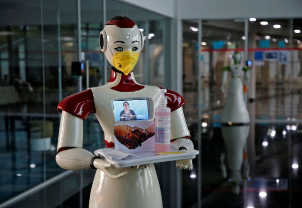 A robot, developed by a start-up firm Asimov Robotics, holds a tray with face masks and sanitizer after the two robots were launched to spread awareness about the coronavirus, in Kochi, India, 17 March 2020 (Photo: Reuters/Sivaram V).