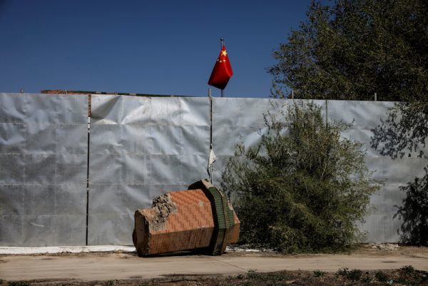 A part of a minaret broken off from the former Xinqu Mosque lies near a Chinese national flag in a yard adjacent to the former house of worship in Changji outside Urumqi, Xinjiang Uyghur Autonomous Region, China, 6 May 2021 (Photo: Reuters/Thomas Peter).