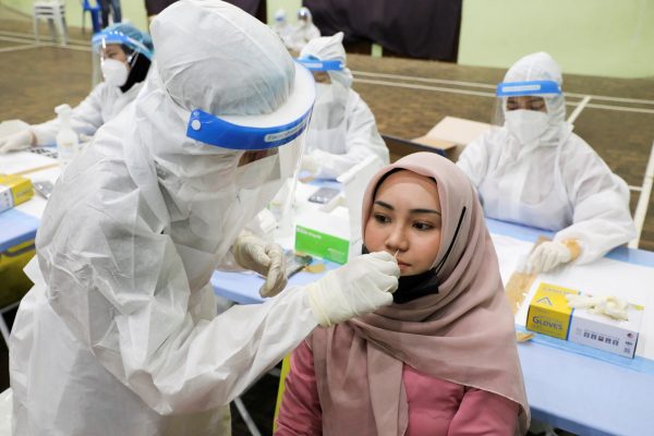 A medical worker collects a swab sample from a woman to be tested for COVID-19 in Kuala Lumpur, Malaysia, 11 May 2021 (Photo: Reuters/Lim Huey Teng).