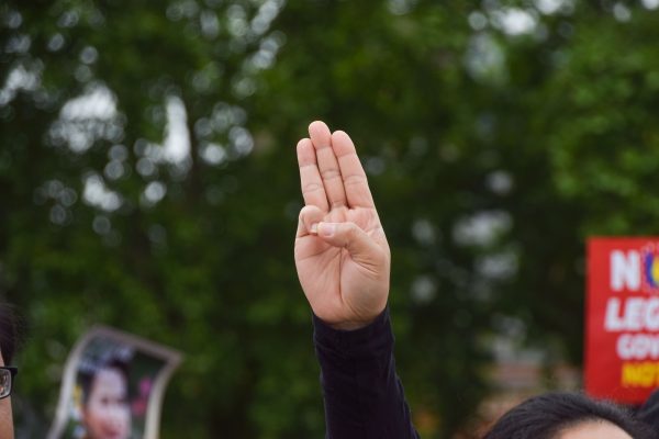 A protester holds up the three-finger salute in Parliament Square during the anti-coup demonstration, London, UK, 19 June 2021 (Photo: SOPA/Vuk Valcic).