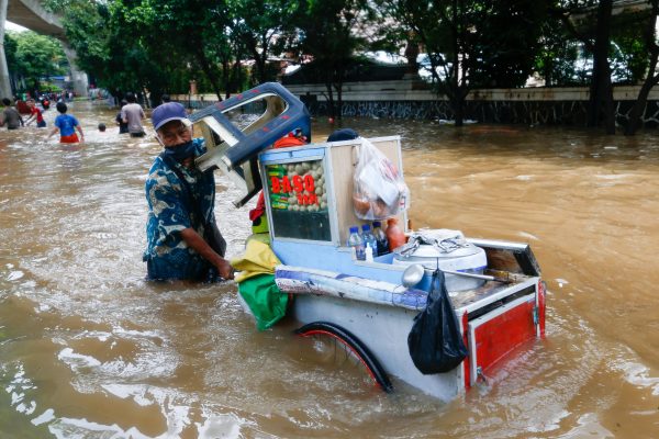 A street vendor pushes his cart through the water in an area affected by floods, Jakarta, Indonesia, 20 February 2021 (photo: Reuters/Ajeng Dinar Ulfiana).