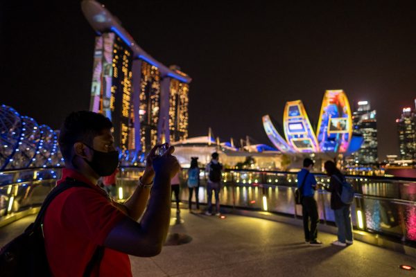 A man stands in front of Marina Bay Sands with his smartphone, in Singapore, 24 February 2021 (Photo: Maverick Asio / SOPA Images/Sipa via Reuters Connect).