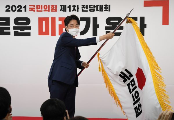 Lee Jun-Seok, new chairman of the main opposition People Power Party (PPP) waves the party flag after elected for leadership race at party headquarters in Seoul, South Korea, 11 June 2021 (Photo: Kim Min-Hee/Pool via Reuters).