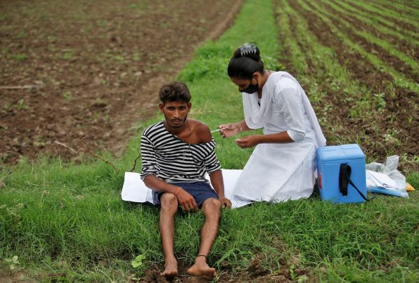 Healthcare worker Jankhana Prajapati gives a dose of the COVISHIELD vaccine to farmer Nareshbhai Dabhi in his field, in Banaskantha, India, 23 July 2021 (photo: REUTERS/Amit Dave)