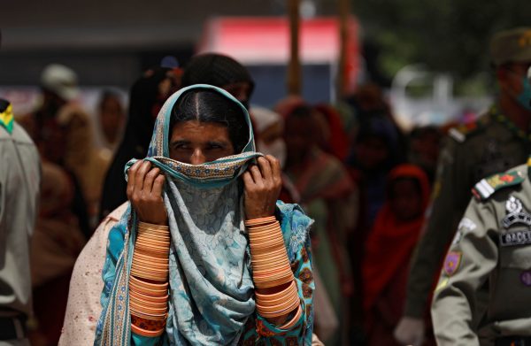 A woman covers her nose and mouth with ? scarf, as she along with others waits to receive cash from a country-wide Ehsaas Emergency Cash program, introduced by the government for vulnerable families due to the ongoing spread of coronavirus disease (COVID-19), in Karachi, Pakistan 11 April 2020 (Photo: Reuters/Akhtar Soomro)