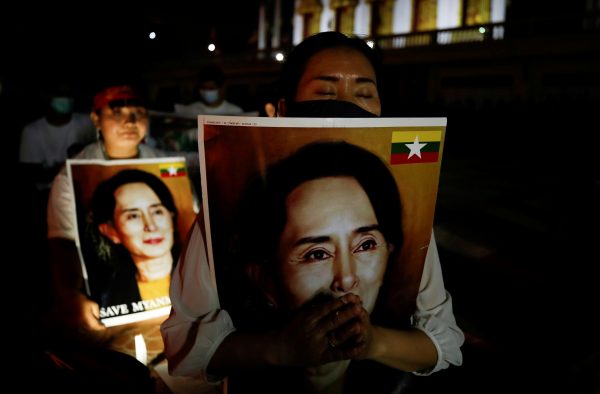 Migrants protesting against the military junta in Myanmar hold pictures of leader Aung San Suu Kyi, during a candlelight vigil at a Buddhist temple in Bangkok, Thailand, 28 March 2021 (Photo: Reuters/Jorge Silva/File Photo).
