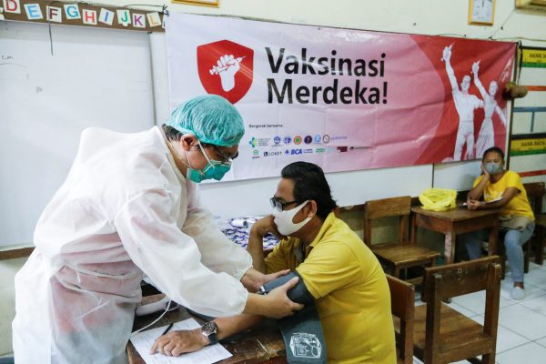 A healthcare worker checks a man before he receives a dose of the coronavirus disease (COVID-19) vaccine during a vaccination program in Jakarta, Indonesia, 17 August 2021 (Photo: Reuters/Ajeng Dinar Ulfiana).