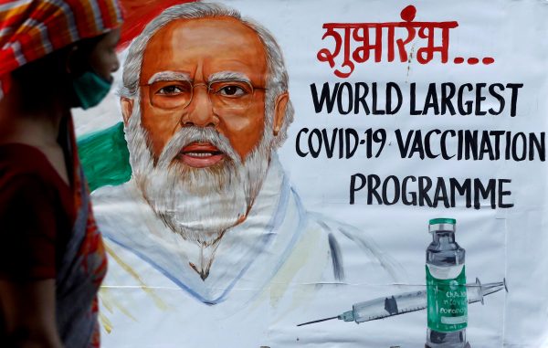 A woman walks past a painting of Indian Prime Minister Narendra Modi a day before the inauguration of the COVID-19 vaccination drive, on a street in Mumbai, India, 15 January 2021 (Photo: Reuters/Francis Mascarenhas).