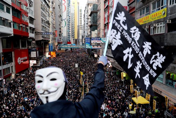 A protester wearing a Guy Fawkes mask waves a flag during a Human Rights Day march, organised by the Civil Human Right Front, Hong Kong, China 8 December 2019 (Photo: Reuters/Danish Siddiqui).