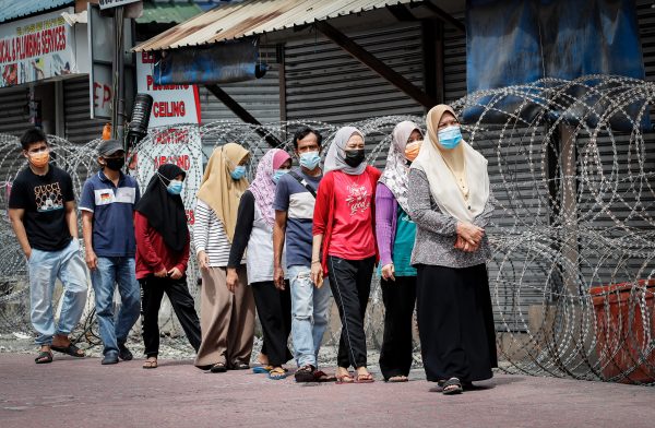 People wearing masks walk in line to go for Covid-19 swab testing at the Segambut Dalam housing area which was placed under the enhanced movement control order (EMCO) due to surge in the number of COVID-19 daily cases recorded. Malaysia government starts to further tighten the movement control and imposes lockdown in state of Selangor and parts of Kuala Lumpur, due to the daily high number of coronavirus infections cases reported (Photo: Reuters/Wong Fok Loy/SOPA Images/Sipa USA).